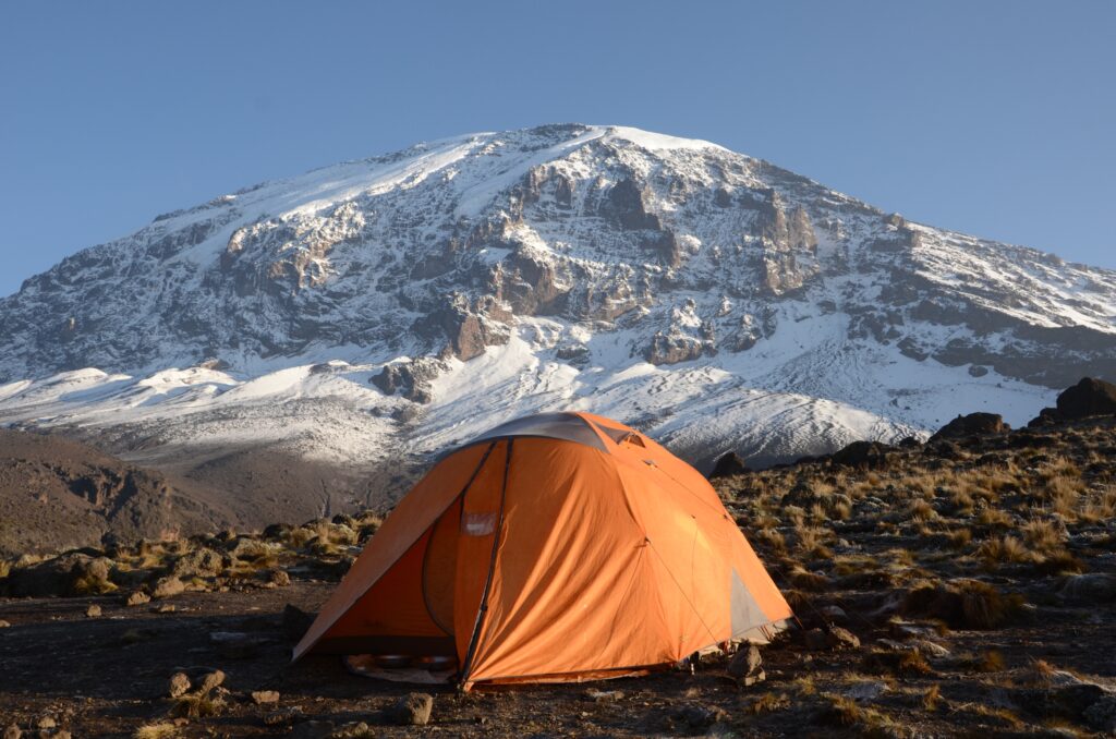 A photo of a tent with Kilimanjaro in the a background covered with snow